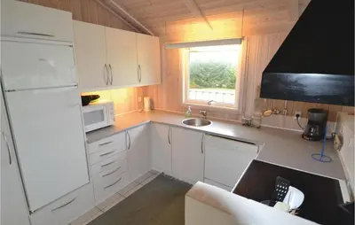 a small kitchen with white cabinets and a window at Holiday Home Blokhus 49 in Blokhus