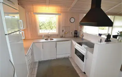 a kitchen with white cabinets and a sink at Holiday Home Blokhus 49 in Blokhus