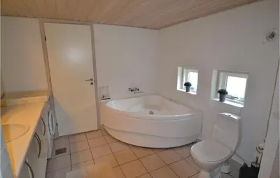 a white bathroom with a tub and a toilet at Holiday Home Blokhus 49 in Blokhus