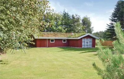 a red house with a grass yard in front of it at Holiday Home Blokhus 58 in Blokhus
