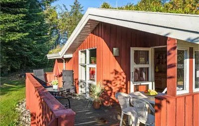 an orange house with a deck with a table and chairs at Holiday Home Blokhus 58 in Blokhus