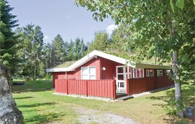 a red cottage with a tree in the yard at Holiday Home Blokhus 58 in Blokhus