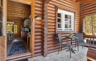 a log cabin with a table and chairs on a porch at Holiday Home Blokhus 59 in Blokhus