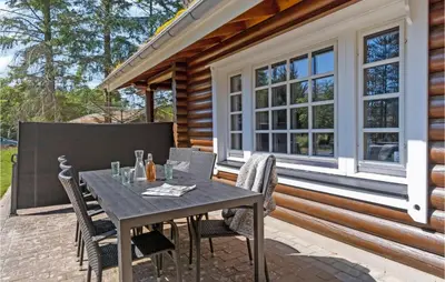 a patio with a table and chairs in front of a house at Holiday Home Blokhus 59 in Blokhus