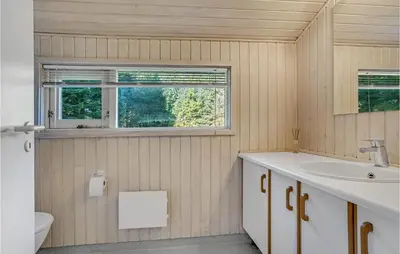 a bathroom with a sink and a toilet and a window at Holiday Home Blokhus 9 in Blokhus