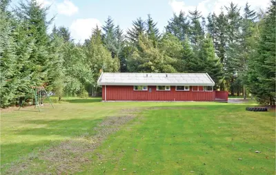 a red barn in a field with a playground at Holiday Home Blokhus 9 in Blokhus