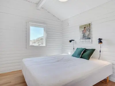 a white bedroom with a large bed and a window at Holiday Home Efra - 400m from the sea by Interhome in Saltum