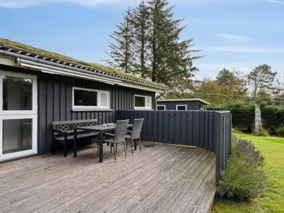a wooden deck with a table and chairs on a house at Holiday Home Sigbritt - 2-6km from the sea by Interhome in Blokhus