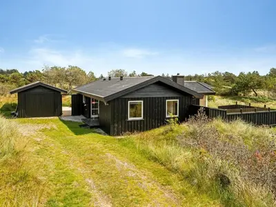 a black house on a hill with a dirt road at Holiday Home Anbritt - 1km from the sea by Interhome in Saltum