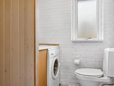 a bathroom with a toilet and a washing machine at Holiday Home Patrik - 200m to the fjord by Interhome in Fur