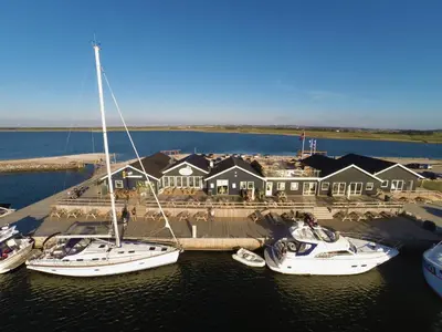 a group of boats docked in the water near a house at Boathouses dk - Besøg os direkte på hjemmesiden in Vinderup