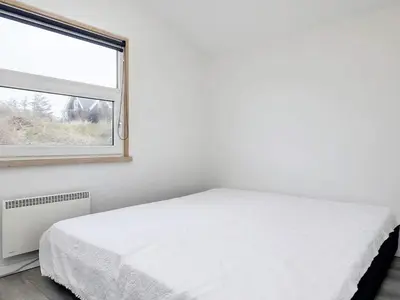 a white bedroom with a bed and a window at 4 star holiday home in Blokhus-By Traum in Blokhus