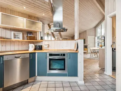 a large kitchen with blue cabinets and a table at Holiday Home Bruni - 400m from the sea by Interhome in Frøstrup