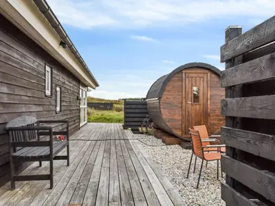 a wooden deck with two chairs and a barrel at Holiday Home Bruni - 400m from the sea by Interhome in Frøstrup