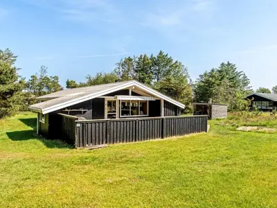 a house on a grassy field with a building at Holiday Home Thrineke - 600m from the sea by Interhome in Saltum