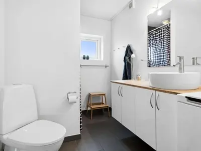 a white bathroom with a sink and a toilet at Apartment Helemine - 400m from the sea by Interhome in Fjerritslev