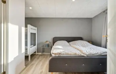 a bed in a bedroom with a gray wall at Nice Home In Roslev With Wifi in Roslev