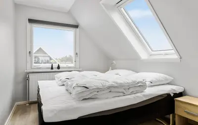 a bed with white sheets in a room with two windows at Lovely Home In Vestervig With Wifi in Vestervig