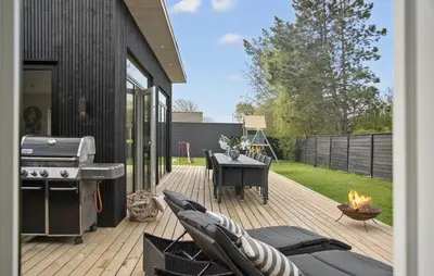 a patio with a grill and a table and a grill at Amazing Home In Blokhus With Sauna in Blokhus