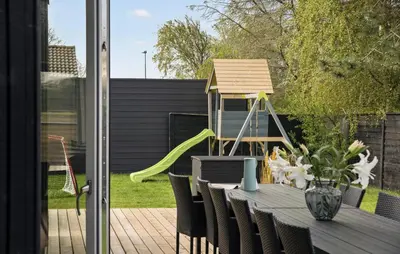 a table and chairs with a slide in a backyard at Amazing Home In Blokhus With Sauna in Blokhus