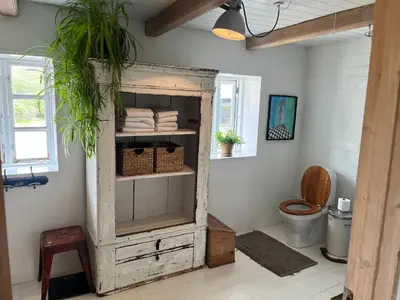 a bathroom with a toilet and a wooden cabinet at The Fishermen's House - charming and close to beach in Vang