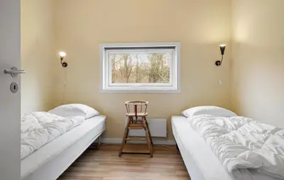 two beds in a room with a chair and a window at Holiday Home Vestervig 44 in Vestervig