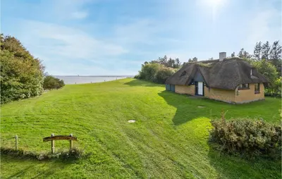 a small house on a grassy hill with the ocean in the background at Holiday Home Thyholm 12 in Thyholm