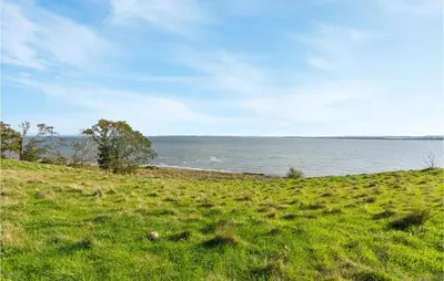 a grassy hill next to a body of water at Holiday Home Thyholm 12 in Thyholm