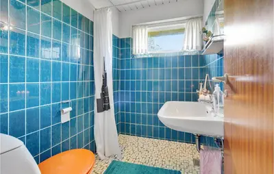 a blue tiled bathroom with a sink and a toilet at Holiday Home Thyholm 12 in Thyholm