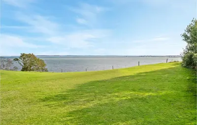 a grassy hill next to a body of water at Holiday Home Thyholm 12 in Thyholm