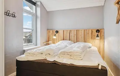 a bedroom with a bed with a wooden headboard and a window at Cozy Home In Vestervig With Sauna in Vestervig