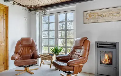 a living room with two leather chairs and a fireplace at 5 Bedroom Gorgeous Home In Thyholm in Thyholm