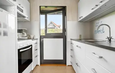 a kitchen with white cabinets and a door with a window at Amazing Home In Øster Assels With Wifi in Øster Assels