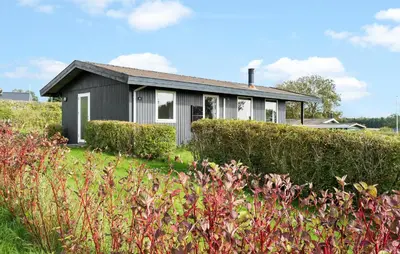 a small house in a field with bushes at Amazing Home In Øster Assels With Wifi in Øster Assels