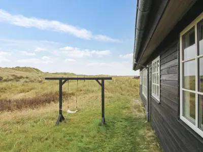 a porch with a swing next to a house at Holiday Home Merina - 150m from the sea by Interhome in Løkken
