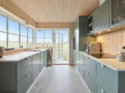a kitchen with blue cabinets and a large window at Holiday Home Merina - 150m from the sea by Interhome in Løkken