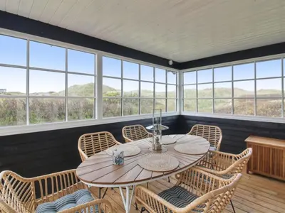 a room with a table and chairs and windows at Holiday Home Merina - 150m from the sea by Interhome in Løkken