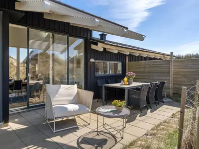 a patio with a table and chairs and a building at Holiday Home Annrike - 400m from the sea by Interhome in Saltum