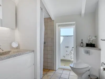 a white bathroom with a toilet and a shower at Holiday Home Annrike - 400m from the sea by Interhome in Saltum