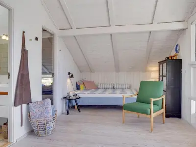a bedroom with a bed and a green chair at Holiday Home Annrike - 400m from the sea by Interhome in Saltum