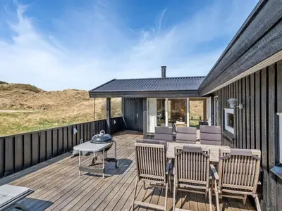 a wooden deck with a table and chairs on it at Holiday Home Nikodina - 200m from the sea by Interhome in Saltum