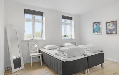 a bedroom with a bed with white walls and a mirror at Nice Home In Roslev With Kitchen in Roslev