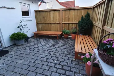 a patio with a wooden bench and potted plants at Centralt by hus Blokhus-Hune til 10 pers privat Gårdhave in Blokhus