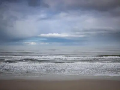 a beach with a cloudy sky and the ocean at Tranquil Beach Retreat - By Traum Ferienwohnungen in Løkken