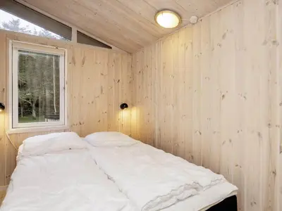 a bed in a wooden room with a window at Tranquil Beach Retreat - By Traum Ferienwohnungen in Løkken