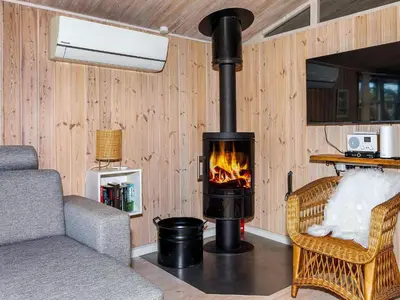 a fireplace in a room with a couch and a chair at Tranquil Beach Retreat - By Traum Ferienwohnungen in Løkken