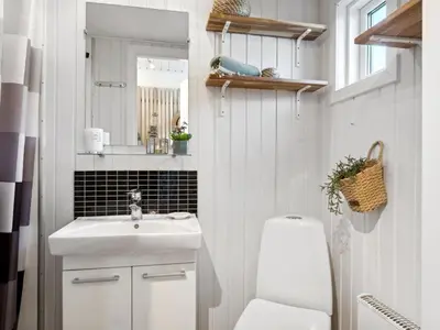 a bathroom with a sink and a toilet and a mirror at Apartment Milly - 150m to the fjord by Interhome in Vestervig
