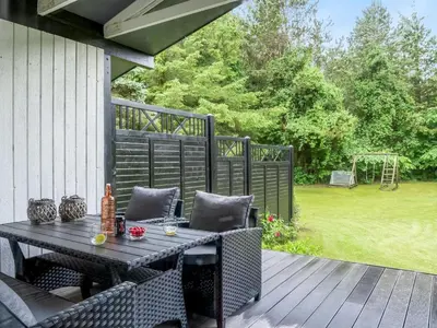 a patio with a table and chairs on a deck at Holiday Home Suri - 200m to the fjord by Interhome in Thyholm