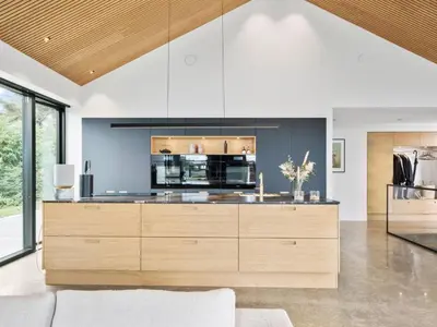 a kitchen with wooden cabinets and a large appliance at Holiday Home Ilja - 800m from the sea by Interhome in Blokhus