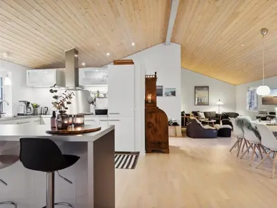 a kitchen and living room with a wooden ceiling at Holiday Home Svante - 600m from the sea by Interhome in Blokhus
